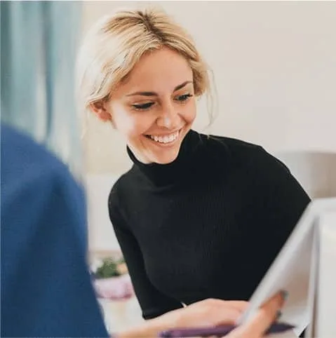 Smiling blonde woman during a consultation at a desk at Cool Clinic, CoolSculpting fat freezing London
